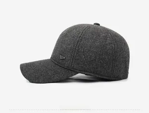 Detail view of dark grey winter baseball cap with thick wool texture and metal side logo