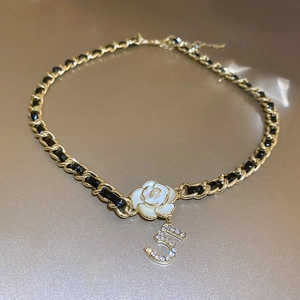 Detail of woven black leather and gold chain necklace with camellia flower and 5 charm