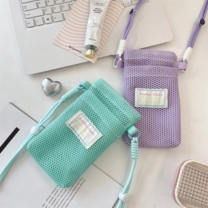 Flat lay of mesh crossbody phone bags in mint and purple with woven ropes and modern decor