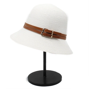 Detailed close-up of a white straw sun hat featuring brown leather belts and golden buckle