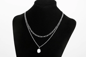 Detail of double-layer stainless steel necklace featuring paperclip chain and pearl