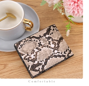 Detailed close-up of foldable wallet featuring snake print texture on a wooden surface