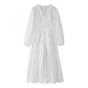 Dettaglio dell'abito bianco con scollo a V, patchwork in pizzo e design con bottoni