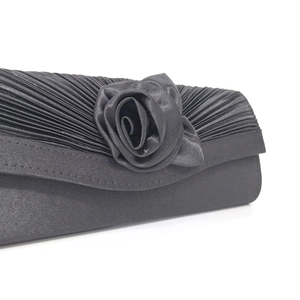 Close-up of black satin evening clutch featuring pleated fabric and handmade 3D rose detail