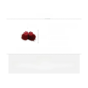Detail view of red resin flower earrings with plush fur balls and silver needles