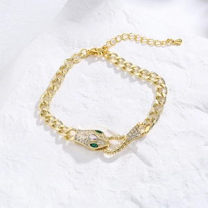 Detail of 18K gold snake bracelet featuring sparkling zircon pave and green gem eyes