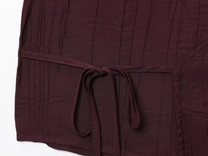 Detail view of wine red crinkled fabric texture and tie-up design on the skirt