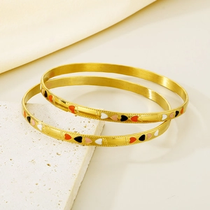 Detail of 18K gold plated stackable bangles featuring colorful heart-shaped enamel patterns