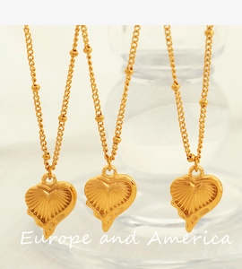 Détail macro du pendentif cœur doré avec motifs radiaux et chaîne à petites billes