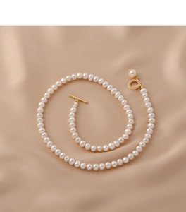 Detail of natural freshwater pearl necklace with gold OT toggle clasp on beige silk