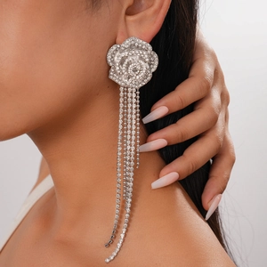 Close-up of model wearing sparkling silver tassel earrings with crystal flower design