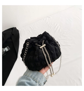Detail of black pleated bucket bag with silver chain strap and large pearl drawstring ends