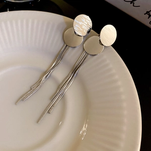 Dettaglio orecchini in argento con lunghe nappe a catena su vassoio in ceramica