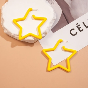 Gros plan de boucles d'oreilles étoiles en acrylique jaune sur un socle décoratif