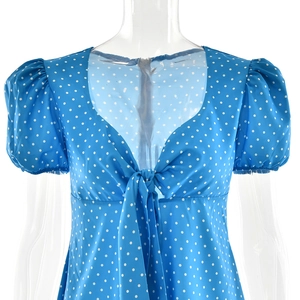 Detail of blue polka dot dress featuring tie-up neckline and puff sleeve design