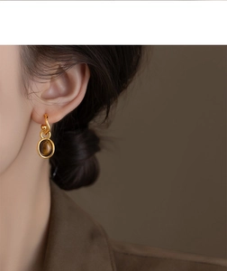 Detail of vintage gold plated oval tiger eye earrings worn on model for premium daily style