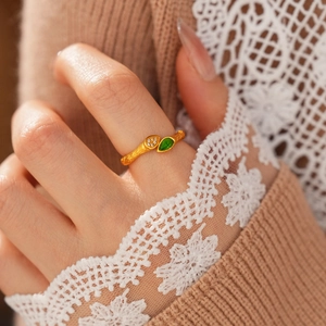 Détail d'une bague vintage plaquée or avec pierre goutte verte et texture branche