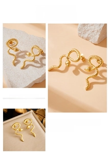 Detail shot of golden snake-shaped stud earrings with intricate scaly texture