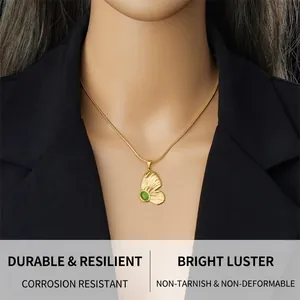Detail of a gold butterfly necklace with a green cat-eye stone on a black blazer