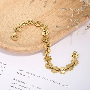 Detailed shot of golden gear-link chain bracelet with lobster clasp on a wooden tray