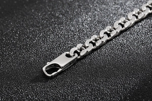 Macro shot of silver stainless steel chain bracelet with clover flower cut-out details