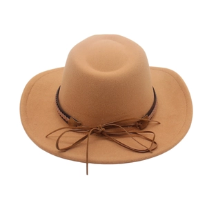 Dettaglio di un cappello in feltro di lana cammello con nastro decorativo in pelle trecciata