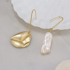 Detail of asymmetric matte gold leaf earring with a baroque white freshwater pearl