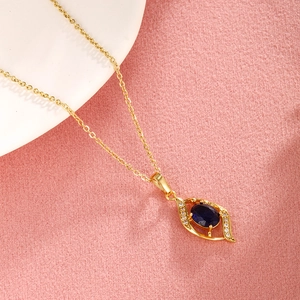 Close-up of golden leaf pendant with deep blue gemstone and sparkling white crystals