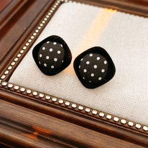Detail of vintage polka dot fabric earrings with black velvet trim on rustic texture