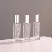 Detailed view of three 10ml glass spray bottles with silver atomizers on a white surface