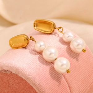 Vue macro des boucles d'oreilles en perles plaquées or 18 carats sur velours rose