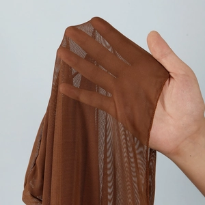 Close-up of brown sheer mesh fabric showing high elasticity and breathable honeycomb texture