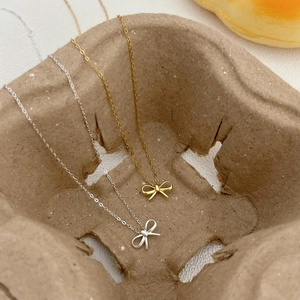 Detail of gold and silver bow necklaces with delicate chain on a vintage paper tray