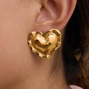 Golden heart-shaped earrings with wrinkled texture on female model in a lifestyle shot