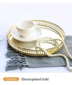 Detailed view of a gold round mirror tray with hollow floral edge on a gray mat
