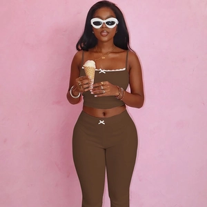 Detail of chocolate brown ribbed knit crop top with white bow and high waist pants