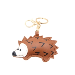 Cute brown PU leather hedgehog keychain with golden metal ring on a white background
