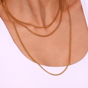 Close-up of 18K gold-plated stainless steel square link chain layered on neck