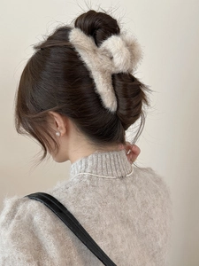 Gros plan d'une grande pince à cheveux en fourrure beige fixant un chignon à l'arrière