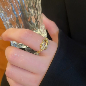 Close-up of a gold knot ring with micro-pave zircons and delicate chain band on finger