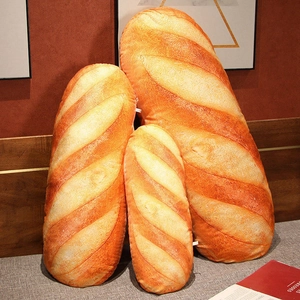 Realistische Baguette-Plüschkissen in drei Größen an einem hölzernen Kopfteil