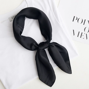 Minimalist black satin square silk scarf tied in a bow on a white shirt background
