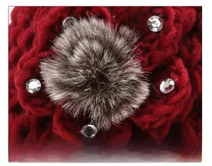 Detail of red knit winter hat featuring sparkly rhinestones and a grey faux fur pompom