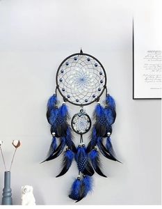 Close-up of bohemian luminous dream catcher with blue feathers and glowing beads on wall