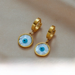 Detailed macro view of gold evil eye earrings with white shell inlay and blue center