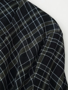 Dettaglio di tessuto scozzese nero con linee verde scuro e morbida trama in cotone