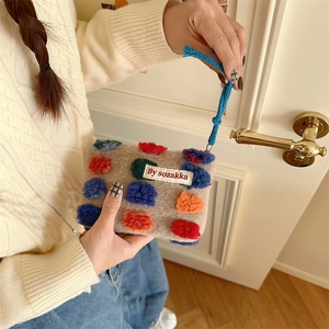 Beige plush bucket handbag with colorful pompoms and blue woven handle for women