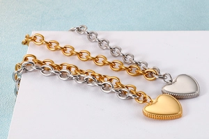 Close-up of heart charm link bracelets in gold and silver finishes on a blue background