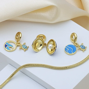 Detail of sea turtle and wave charms with blue enamel on a golden snake chain