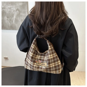 Detail view of brown checkered tote bag with puppy embroidery on female shoulder